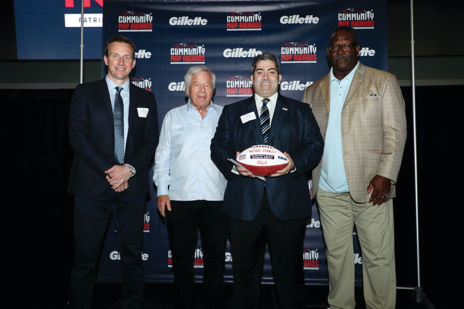 LOCAL MVP: Procter & Gamble’s VP of Grooming, North America, John Claughton (far left), Patriots Chairman and CEO Robert Kraft and Patriots and Pro Football Hall of Famer Andre Tippett congratulate Michael Crawley of Cranston, for being selected as a 2022 Myra Kraft Community MVP Award winner. During the June 8 luncheon, the Kraft family, the Patriots Foundation and Gillette awarded $275,000 in grants to 26 New England nonprofits. The Freiderich’s Ataxia Research Alliance received a $10,000 grant in honor of Crawley’s volunteer efforts.